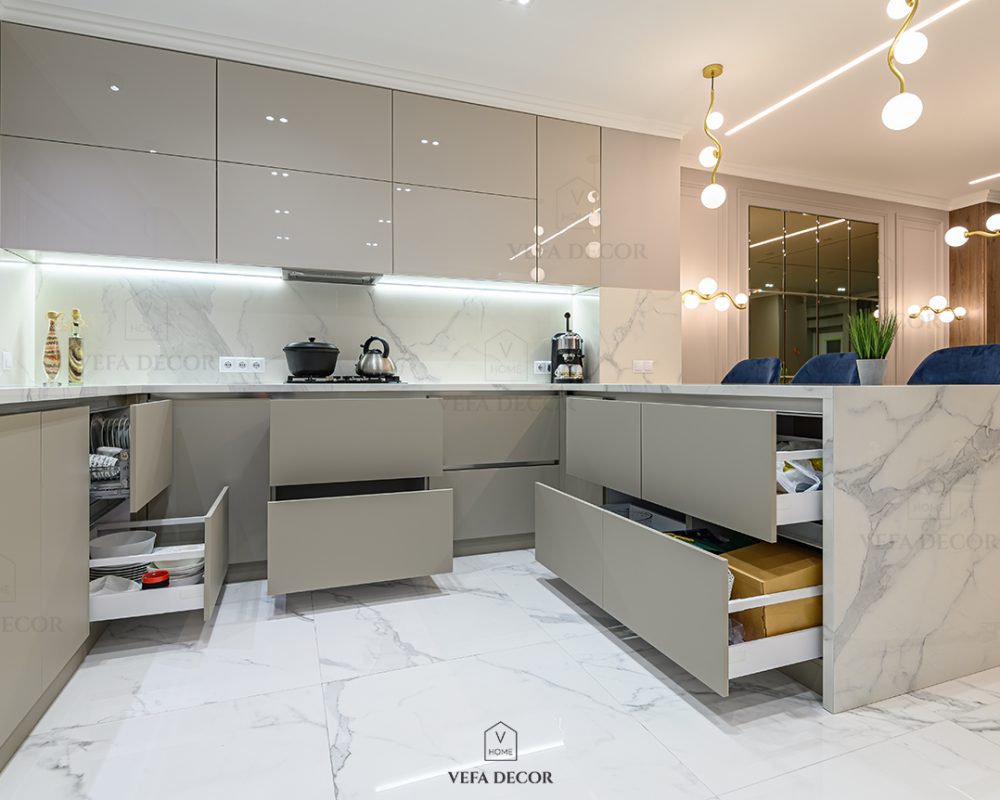 Open drawers at well designed large modern white wood and marble kitchen united with living room as a pert of studio flat